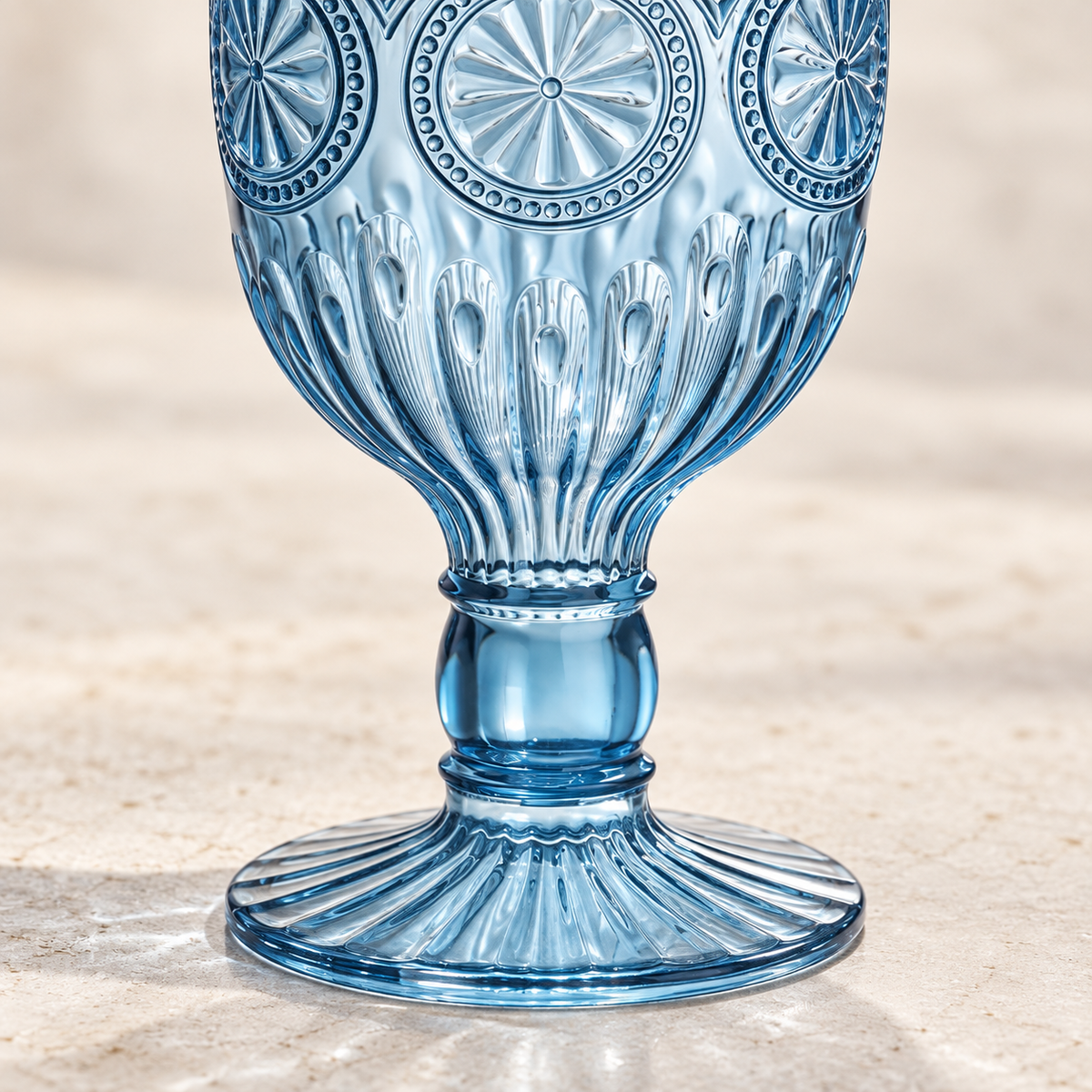 Close-up of sunflower embossing, short stem and fluted foot on a smoky blue plastic goblet