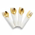 Pre-rolled gold plastic cutlery wrapped in white napkins fanned on white
