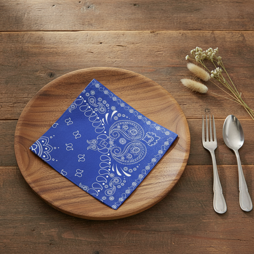 Blue paisley bandana paper napkin on a wood charger at a rustic western place setting