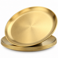 Four gold-tone stainless steel plates on white, with one tilted above three nested plates, showing the shallow brushed well and plain narrow rim.