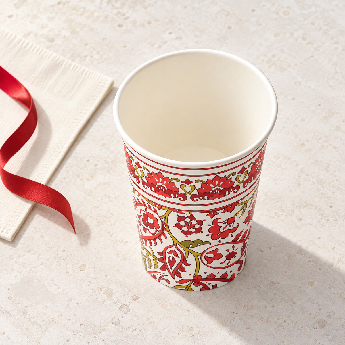 Elevated front view of a Festive Paisley paper cup showing its rim and interior; styling props are not included.