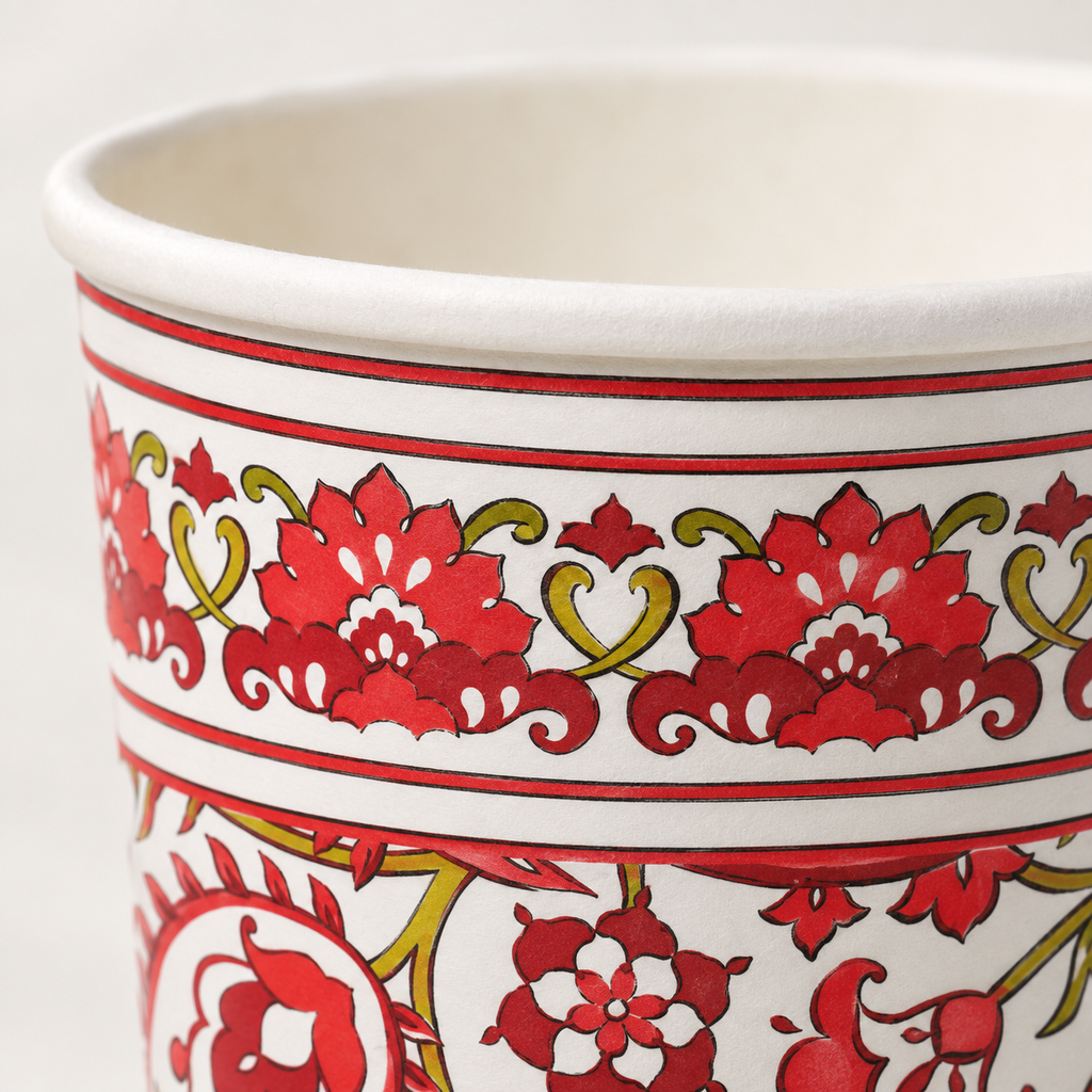 Close view of the rolled rim and red-and-green paisley border on the paper cup.