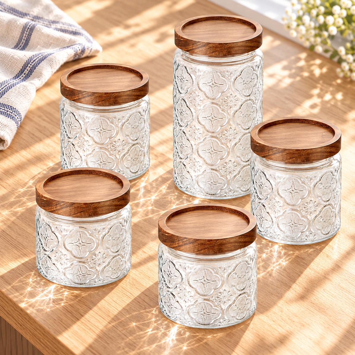 Five vintage-textured glass storage jars with wood lids in a bright alternative view