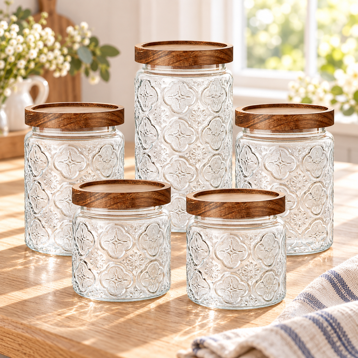 Five vintage-textured glass canisters with wood lids in a bright kitchen setting