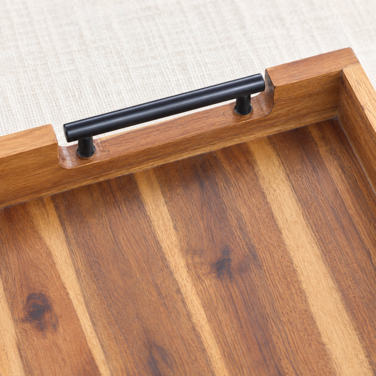 Close-up of acacia wood serving tray with metal handles showing its surface and construction