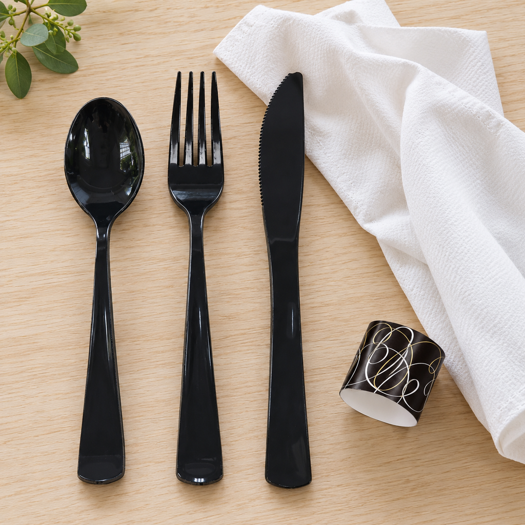 Black cutlery laid out with a white napkin and its printed band.