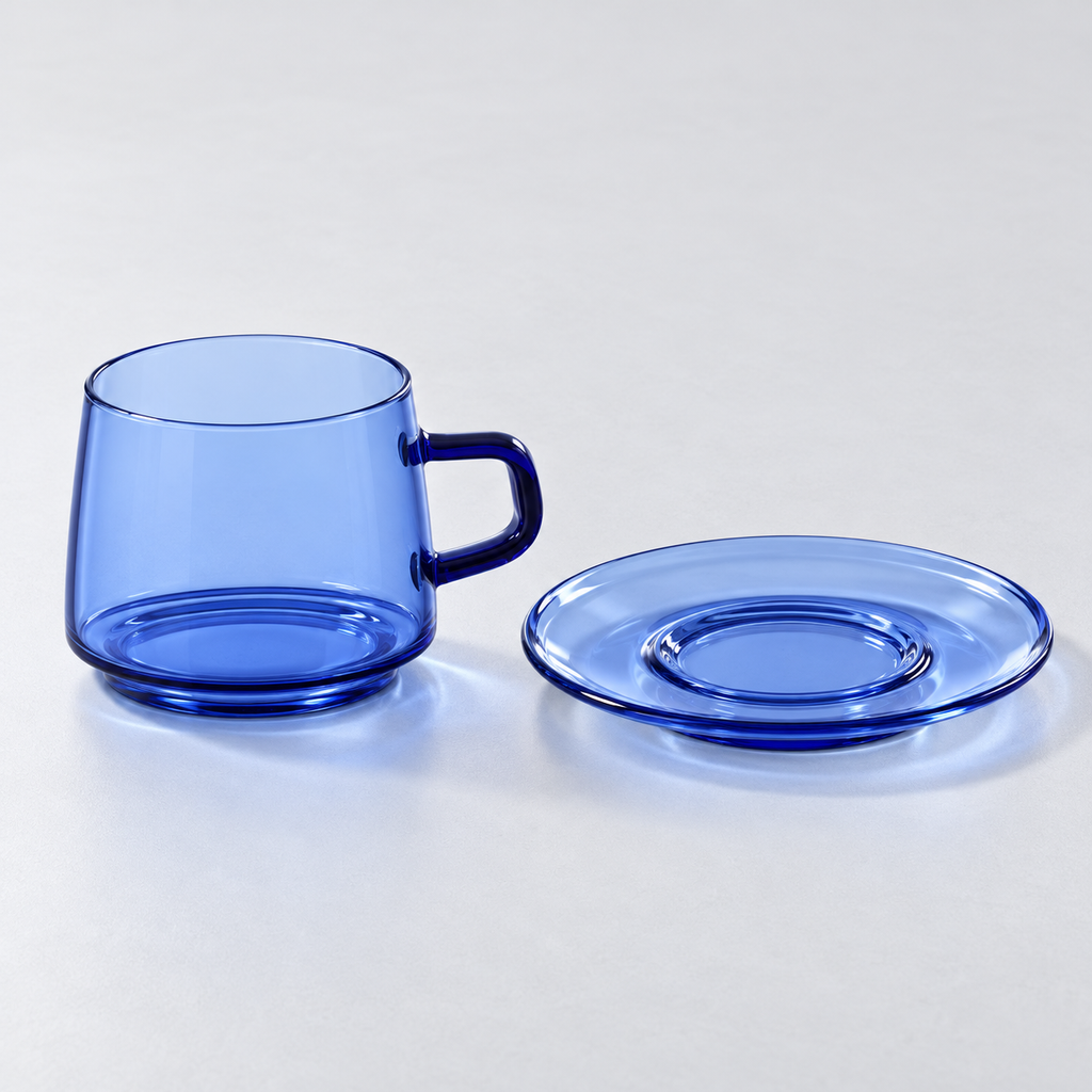 Blue transparent glass cup and matching saucer displayed separately on a light background; one cup-and-saucer set.
