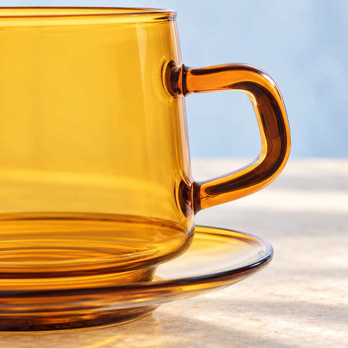 Close view of the Yellow amber-toned glass cup, handle and saucer; Blue option is not pictured.