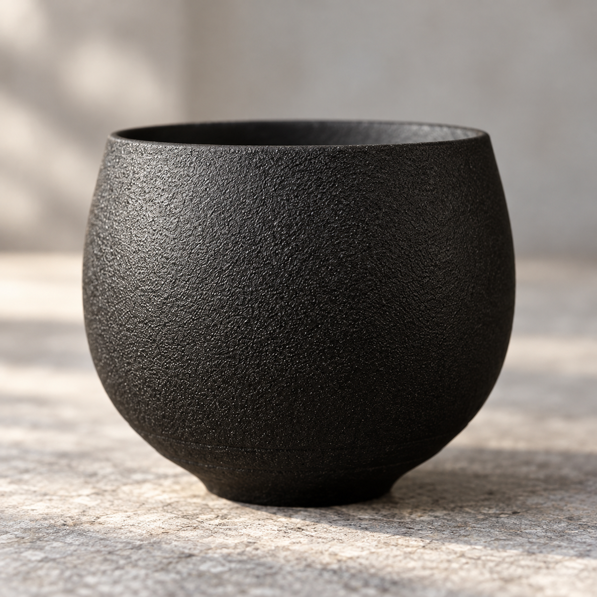 Side view of the black textured pottery cup from the five-piece set.