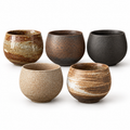 Five-piece textured pottery tea cup set in its five actual glazes on white; this is one fixed set.