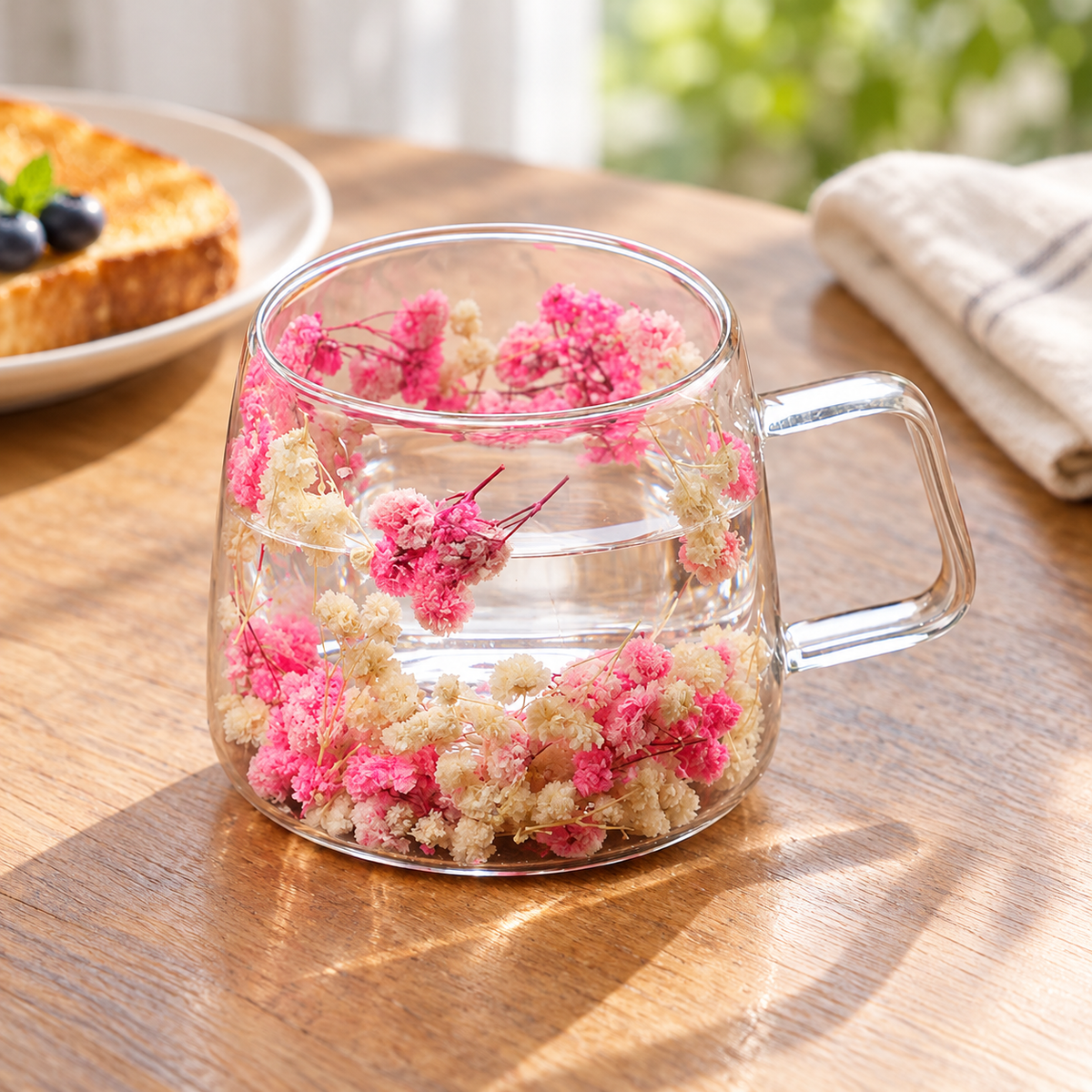 Floral double-wall glass cup with clear water at breakfast; food and linens are styling props.