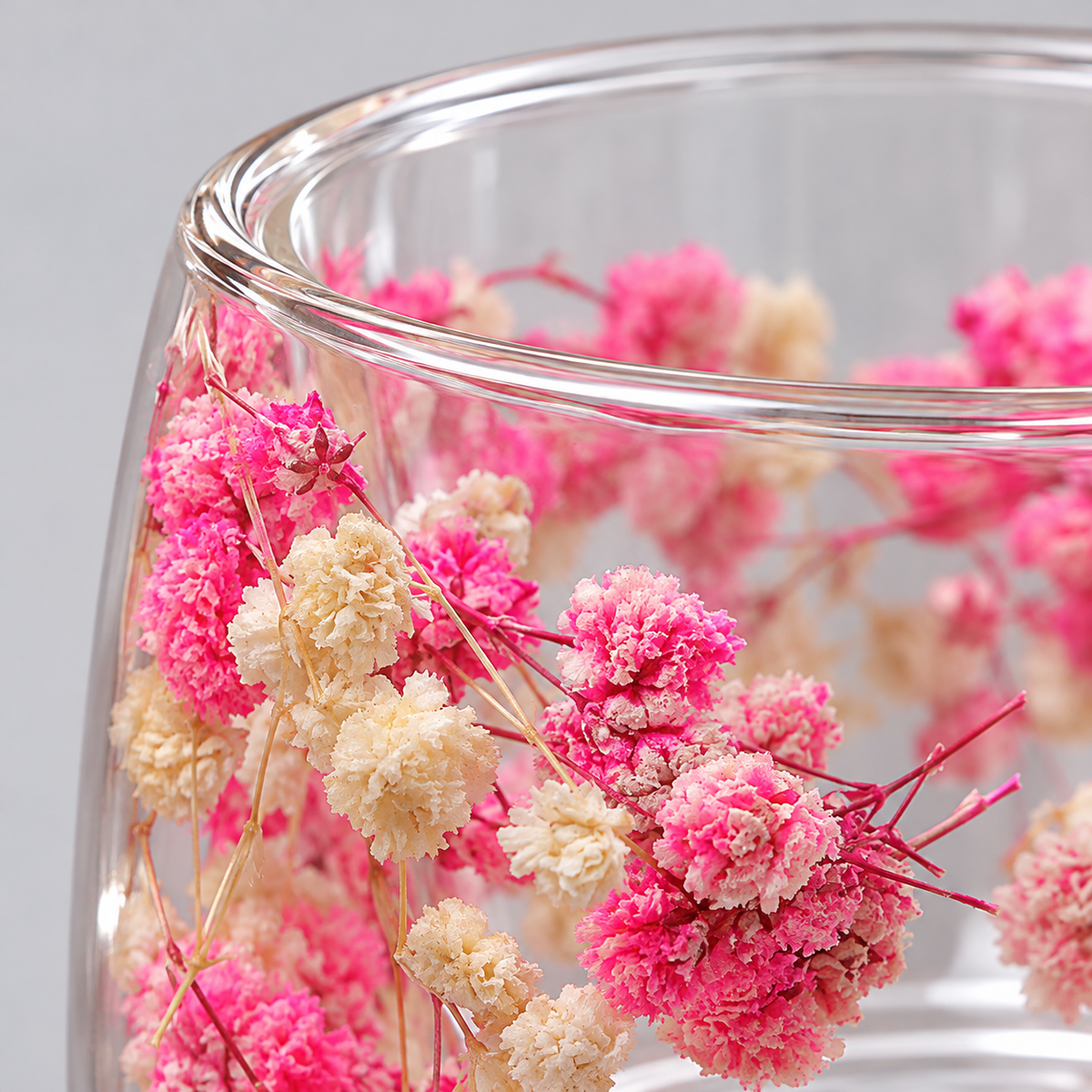 Close detail of clear glass rim and pink-and-cream flowers encased outside the drinking chamber.