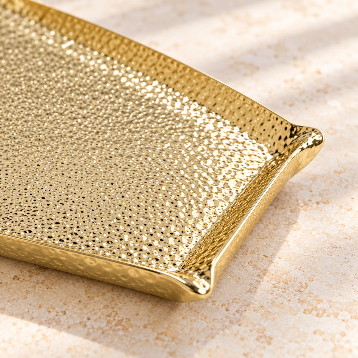 Close view of the gold hammered surface and corner of the Square Large serving tray; rectangular options are not pictured.