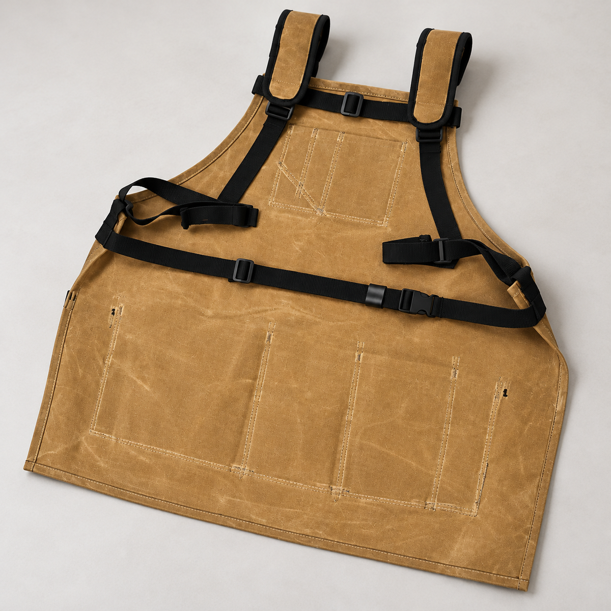 Back of the khaki waxed-canvas apron showing source-matched black harness and waist buckle.