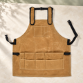 Khaki multi-pocket work apron with padded shoulder straps; tools and styling accessories are not included.