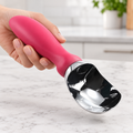 Pink-handled ice cream scoop held to show its form and relative scale.