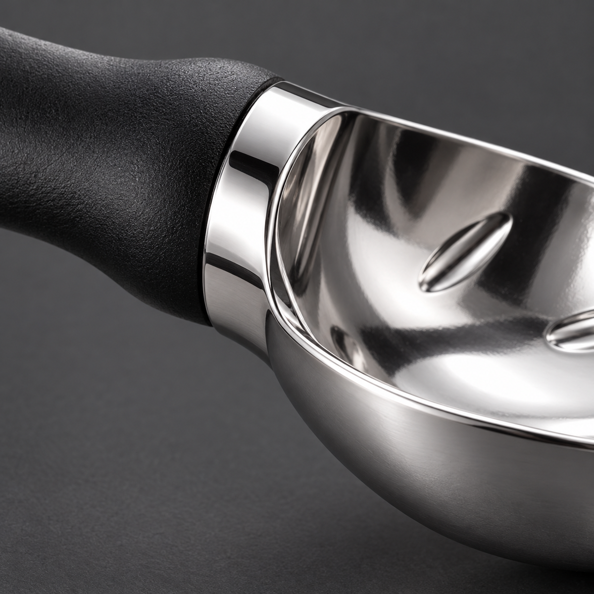 Close detail of the black scoop's metal bowl and handle junction.
