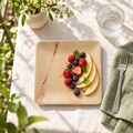 Square palm leaf plate with pear and berries on a balcony linen table. Food and styling props are not included.