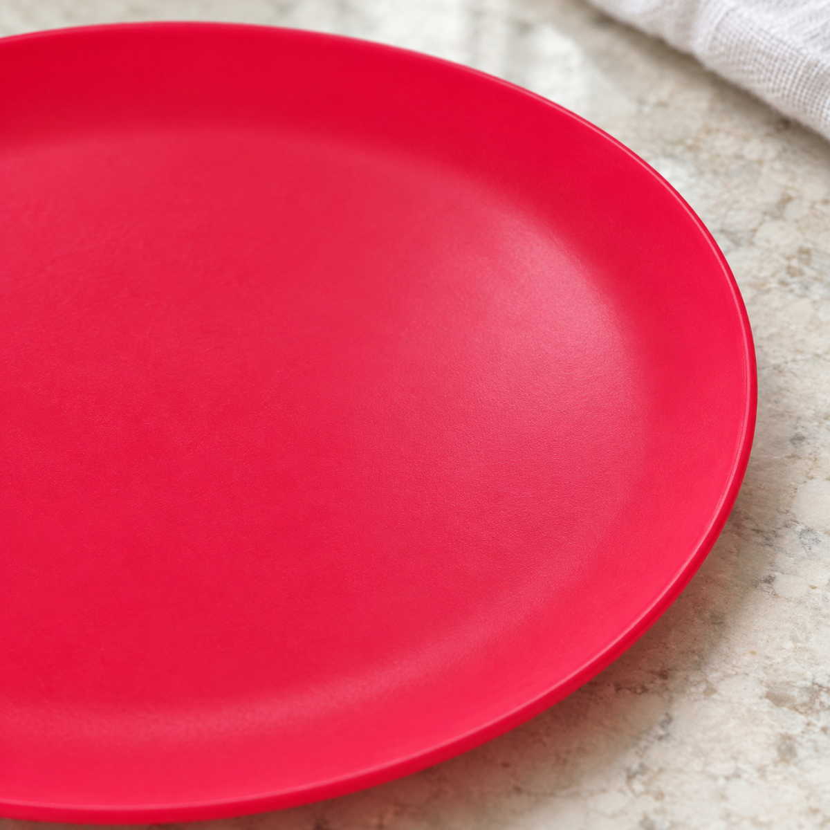 Close view of the shallow well and plain rim of a red-pink plate.