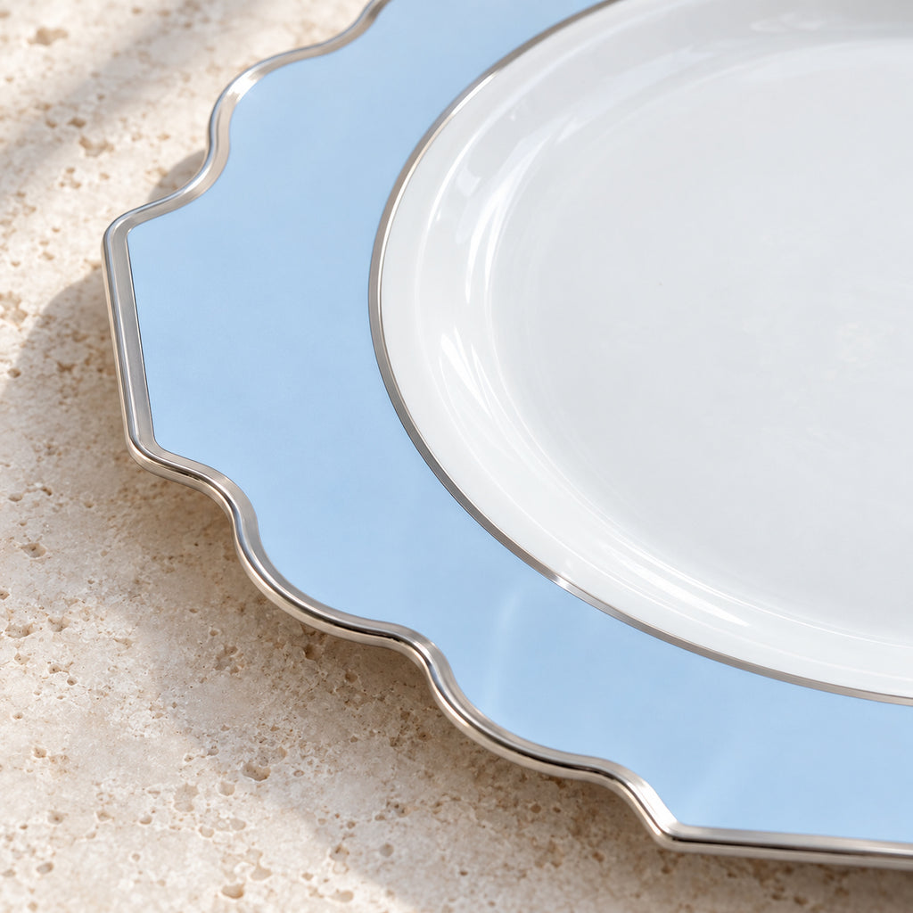 Close view of the pale-blue border, silver inner ring and ornamental silver edge of a white appetizer plate.