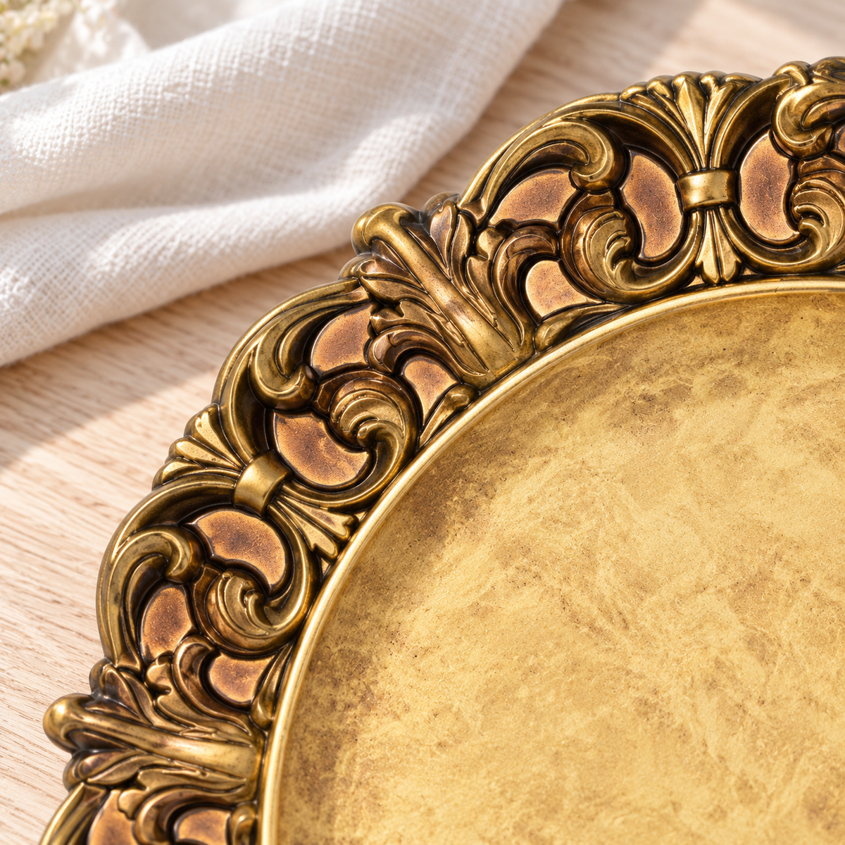 Close-up of the antique gold charger’s raised scroll and leaf border with dark antiqued grooves and solid copper-gold recesses.