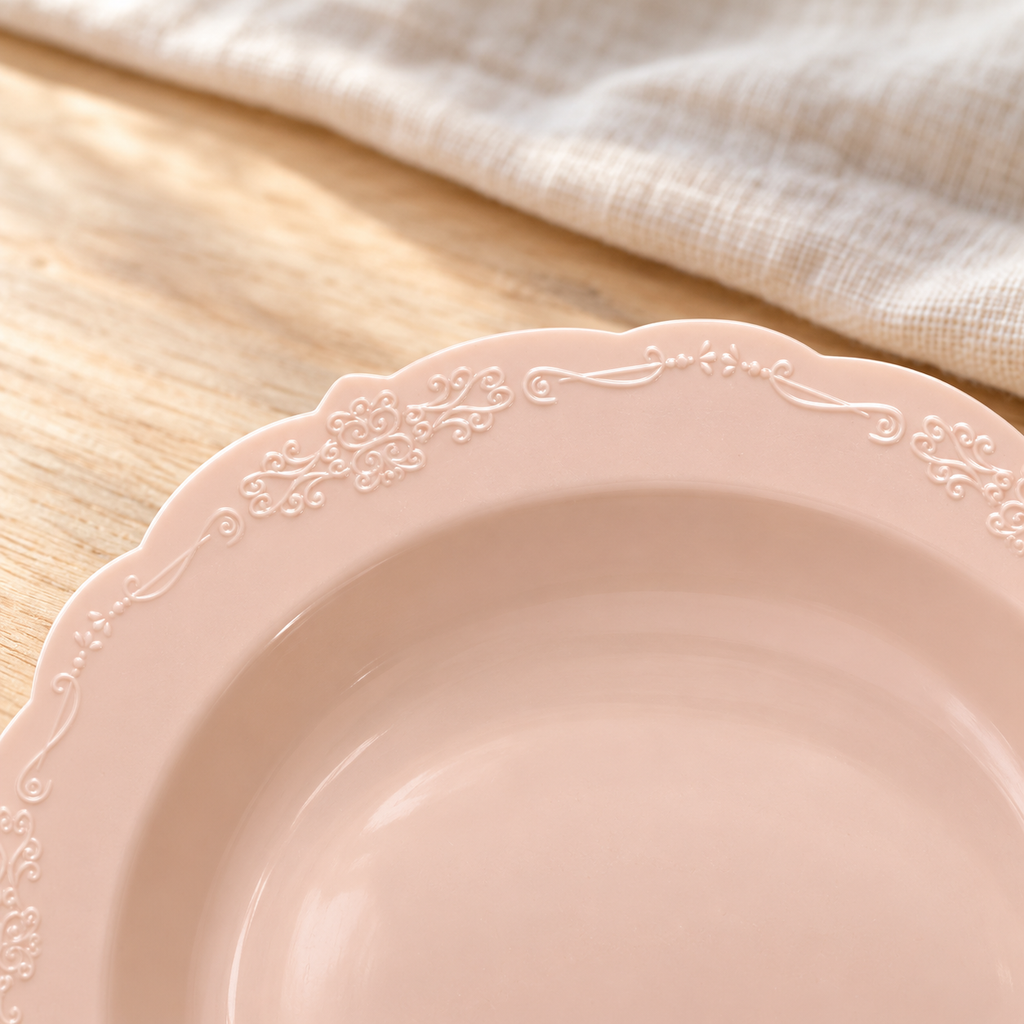 Close view of the delicate embossed scroll pattern and scalloped edge of a blush soup bowl.