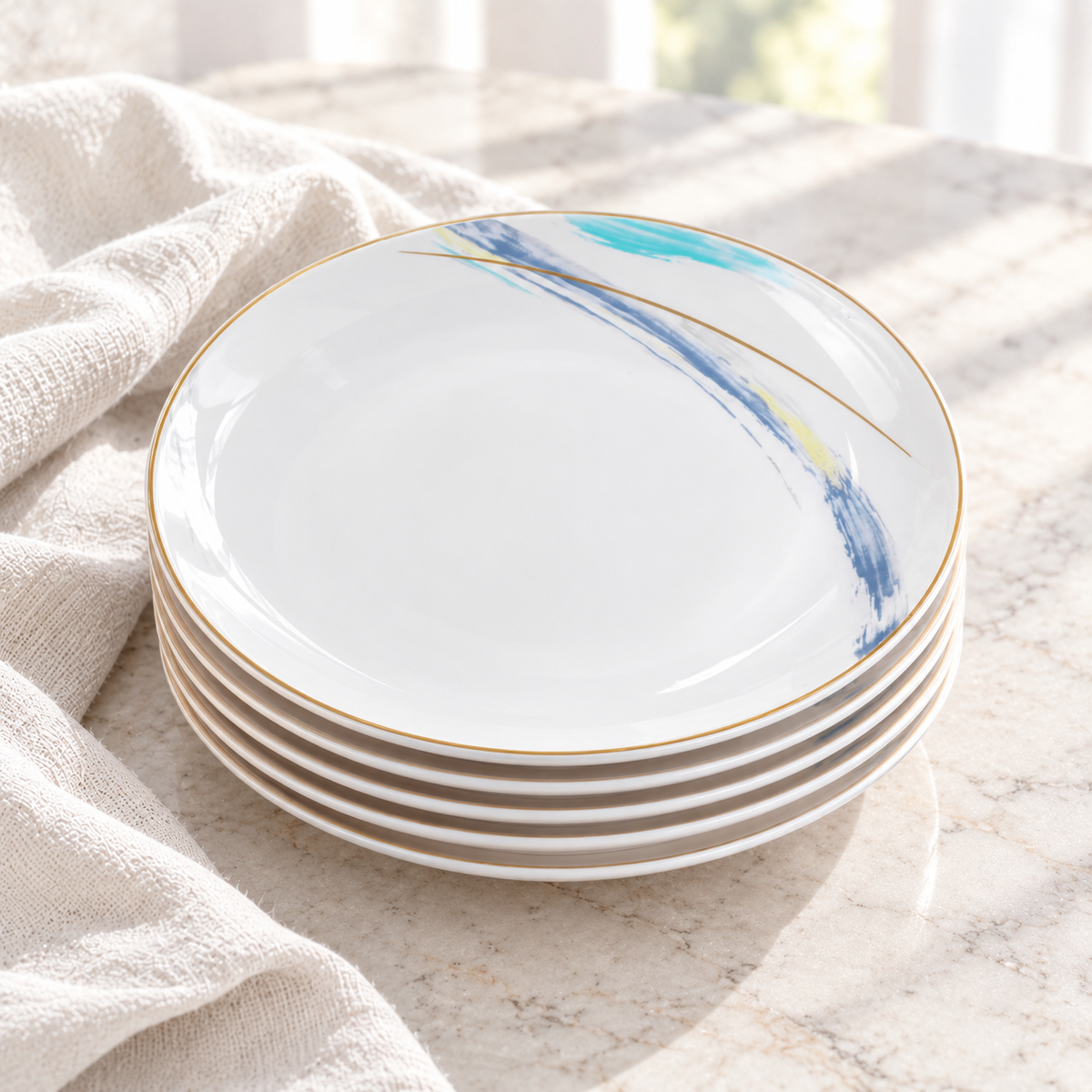 Stacked Gilded Edge ceramic plates showing shallow white edges and the decorated upper face in daylight. Linen is a styling prop. Representative arrangement from the set.