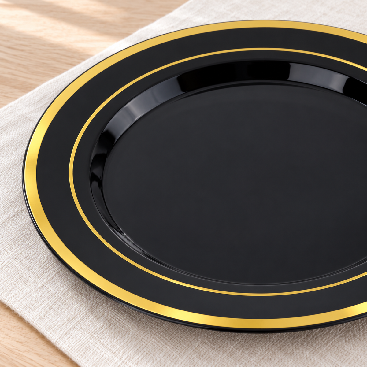 Close view of the broad outer gold band and fine inner gold ring on a glossy black plate. Representative arrangement; styling props not included.