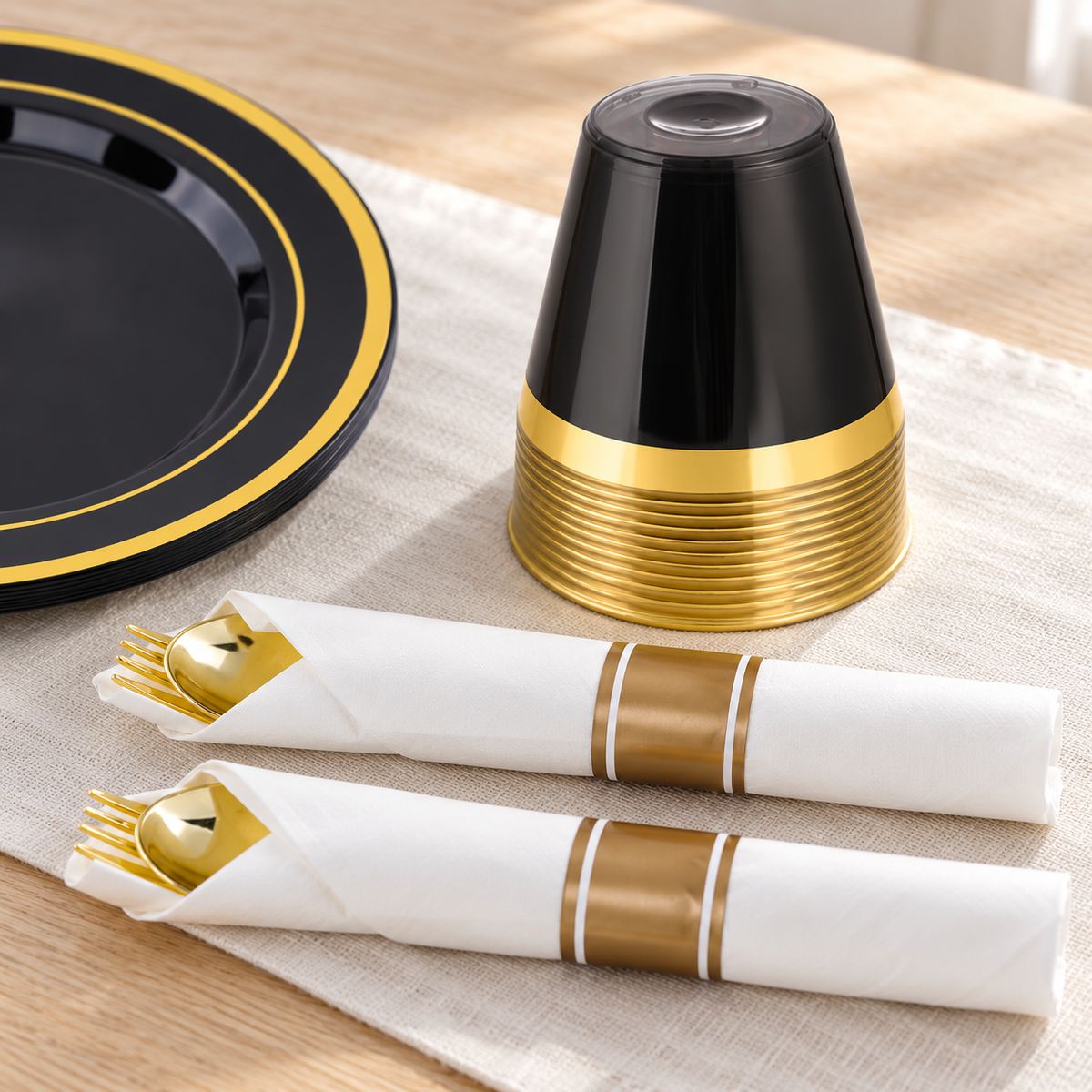 Dark inverted gold-rim cup stack beside white-and-gold wrapped cutlery with only partial gold utensil heads visible. Representative arrangement; styling props not included.
