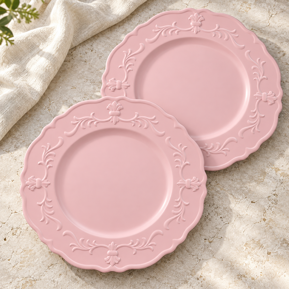 Two empty pink scalloped chargers on pale stone with linen. Representative arrangement from the set.