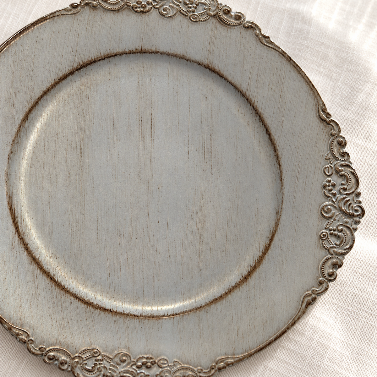 Shallow center-finish detail showing antique grey decorative charger with distressed finish and ornate scroll rim.