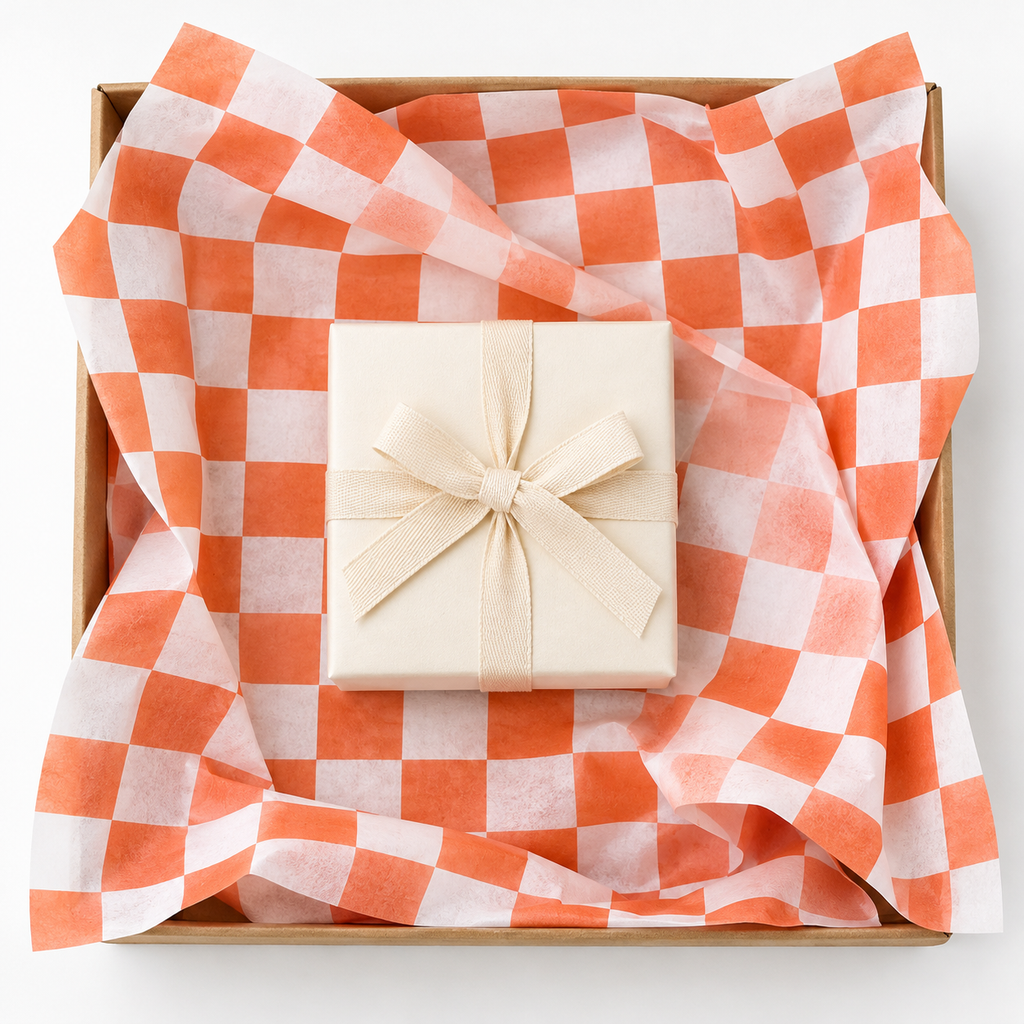 Orange and white check tissue paper, overhead photograph, SKU B0DCBSMWY4. Representative sheets from 100-sheet pack; styling not included.