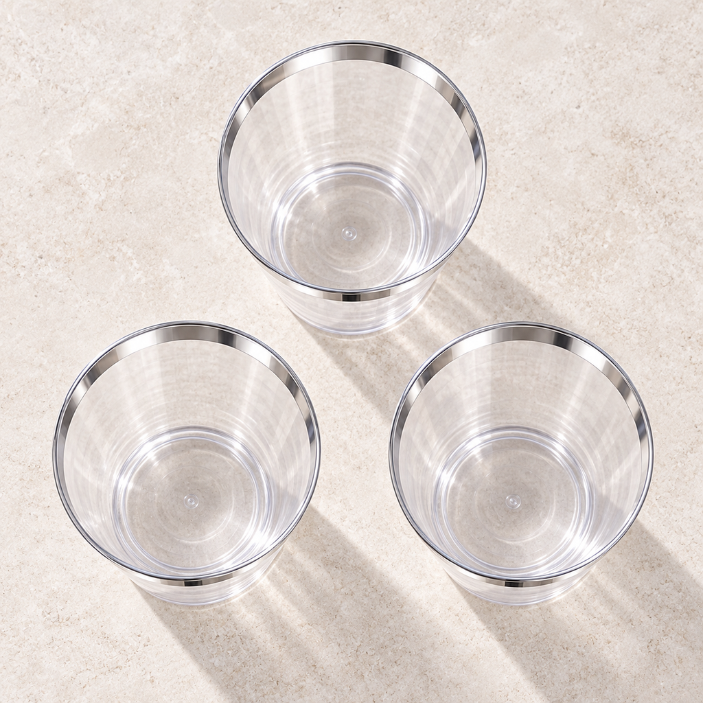 High-angle view into three empty clear plastic tumblers with metallic silver rims.