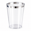 Single empty clear tapered plastic party cup with a narrow metallic silver rim against white.