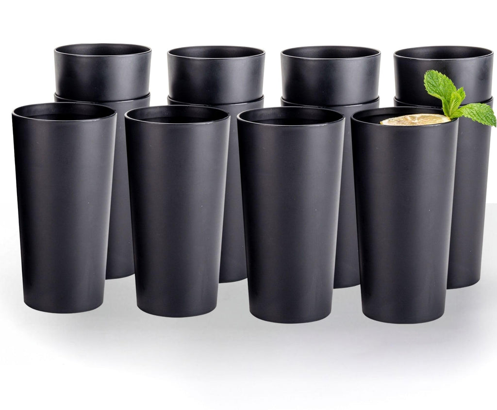 Twelve matte black plastic tumblers arranged on a white background, with a lemon and mint drink in one cup. Drink and garnish not included.
