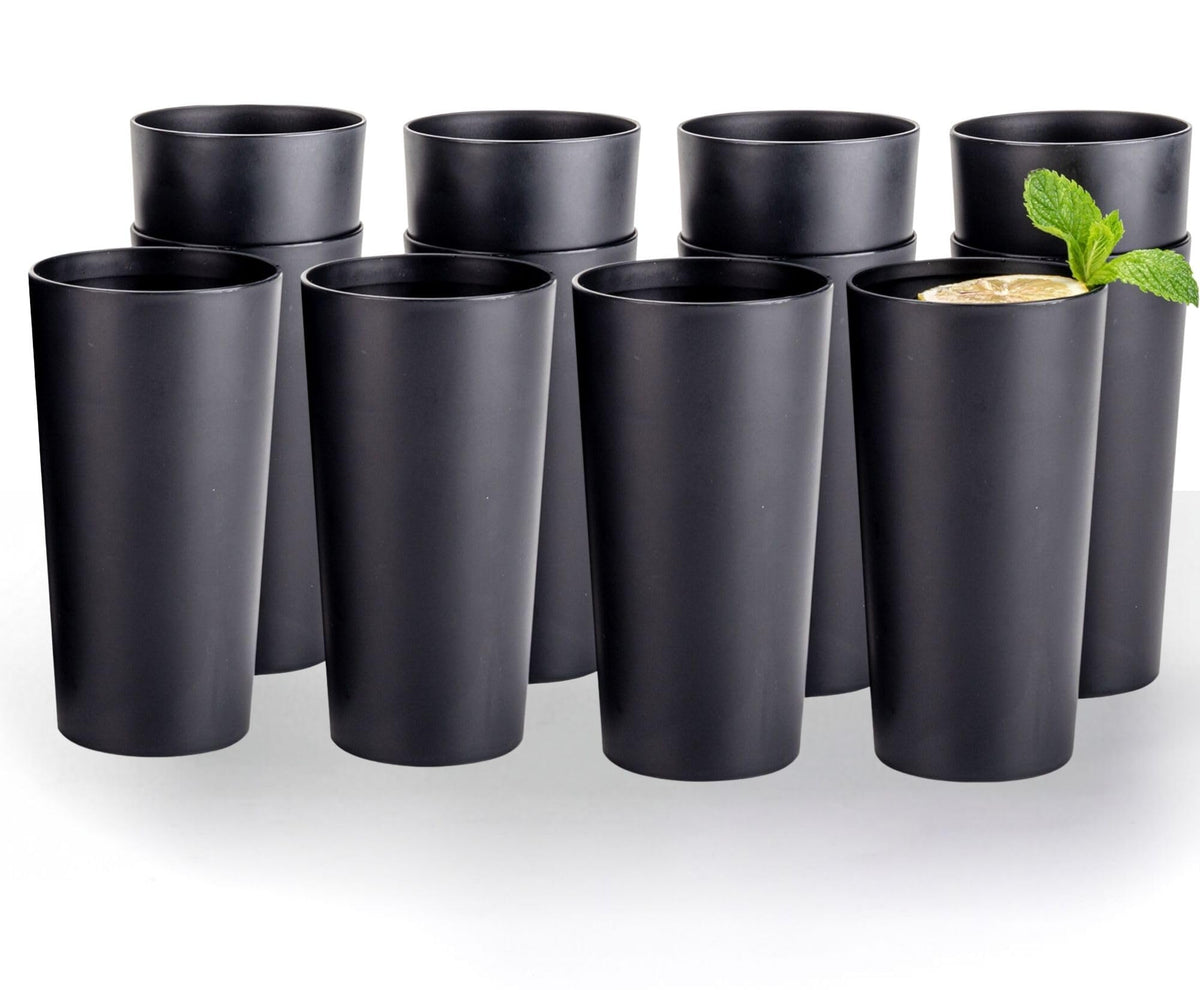 Twelve matte black plastic tumblers arranged on a white background, with a lemon and mint drink in one cup. Drink and garnish not included.