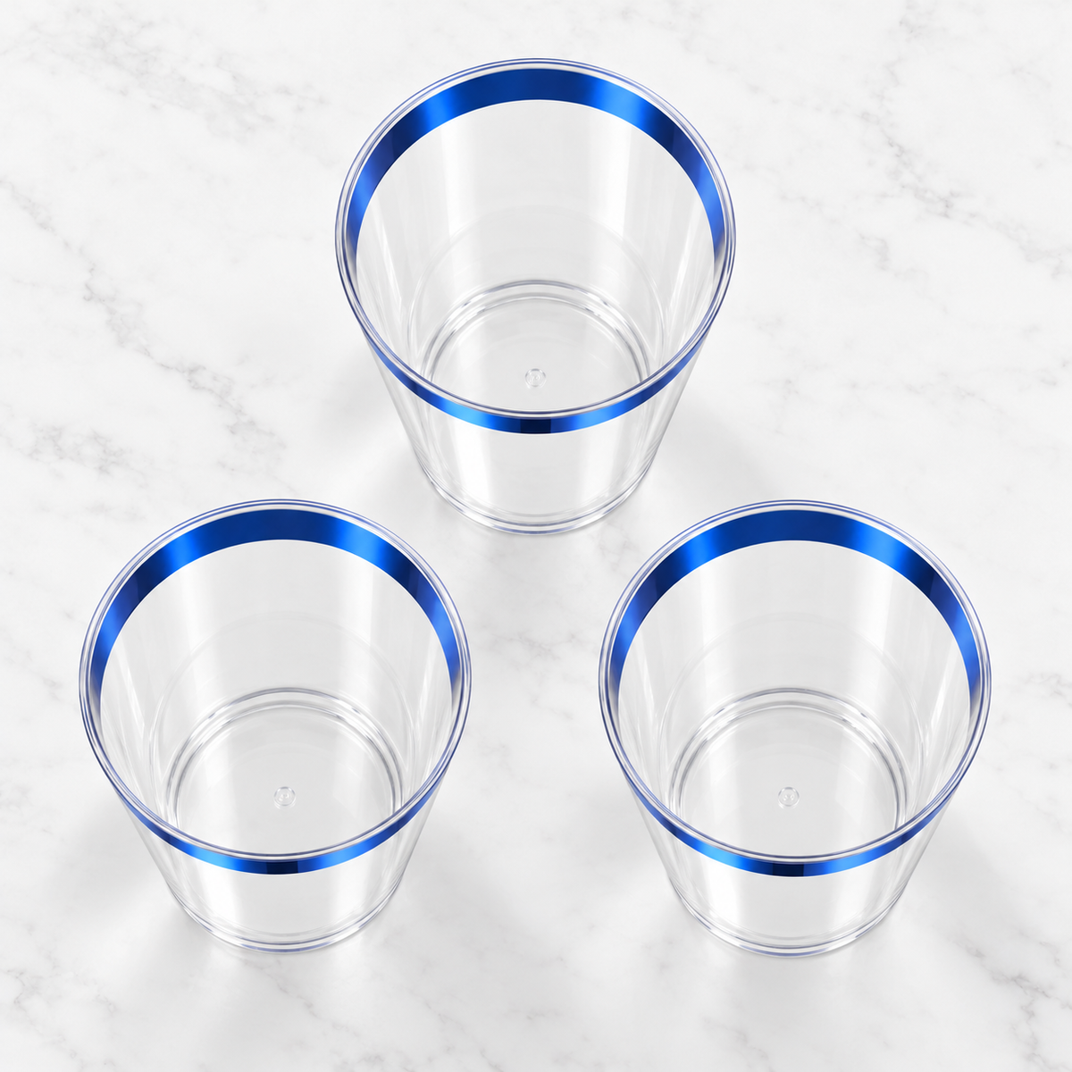 High-angle view into three empty clear tapered plastic tumblers with metallic blue rims.