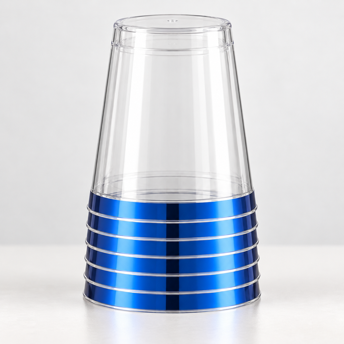 Short inverted nested stack of clear tapered plastic tumblers showing metallic blue rim bands and thin clear lips.