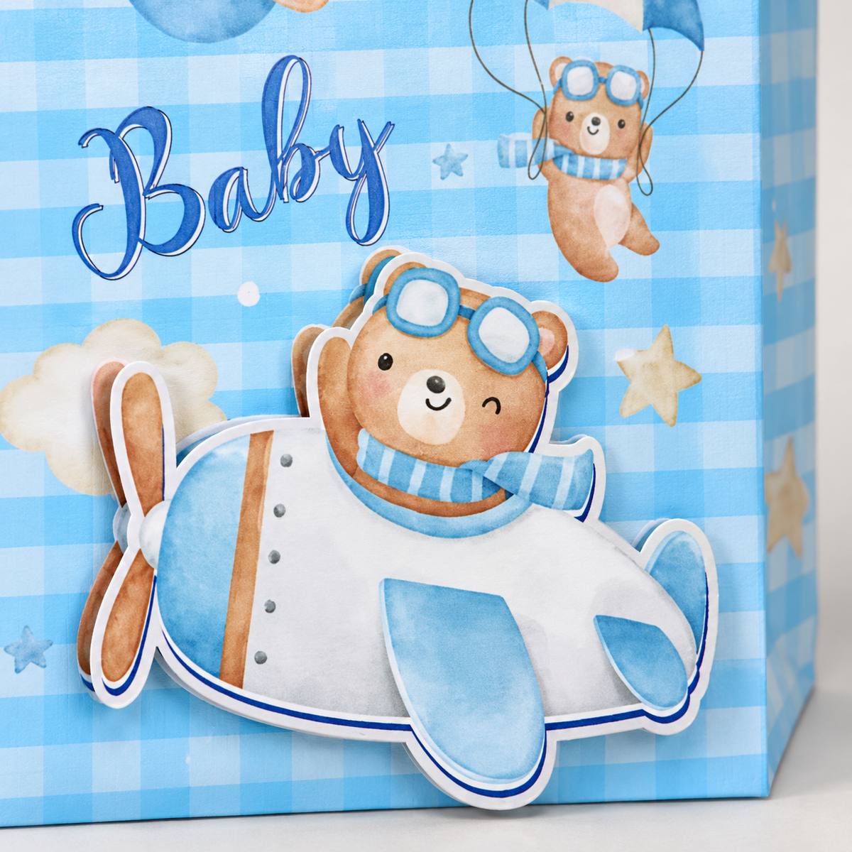 Close-up of the blue gift bag's layered bear airplane paper decoration and gingham print.