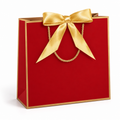Red paper gift bag with gold border, satin bow and twisted gold cord handle on white background.