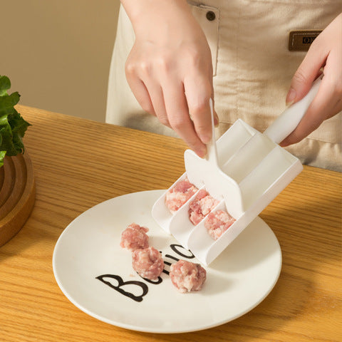 Hands using the paddle to push three meatballs off the scoop onto a white plate