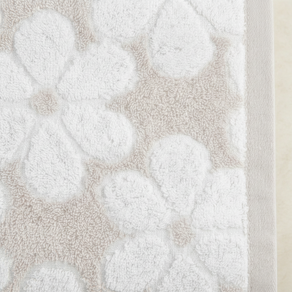Close-up of white six-petal floral jacquard weave on beige terry bath towel