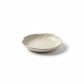 Cream handmade ceramic irregular tasting plate with wavy rim on a white background