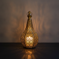 Foratura pierced-metal Moroccan candle lantern glowing on a dark slate surface