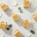 Gold laser-cut filigree favor boxes flat-lay with rose petals and eucalyptus
