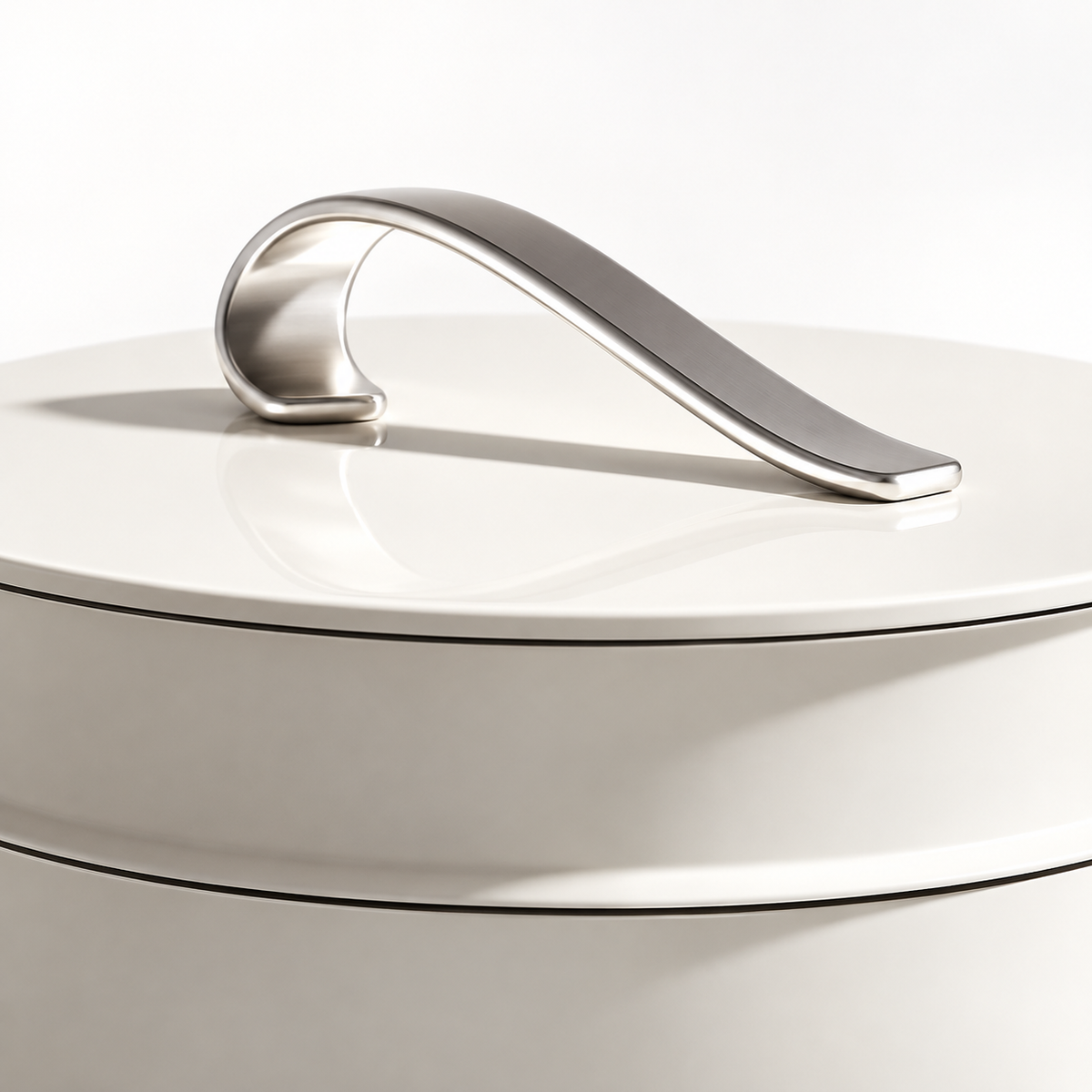 Curved silver lid handle and upper rim detail on white cookware