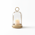 Campana glass cloche candle dome with antique gold-bronze base and ring handle, candle glowing inside