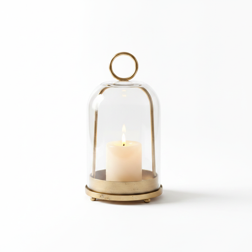 Campana glass cloche candle dome with antique gold-bronze base and ring handle, candle glowing inside