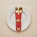 Gold plastic cutlery set pre-rolled in a red napkin with gold band on a gold-rimmed plate