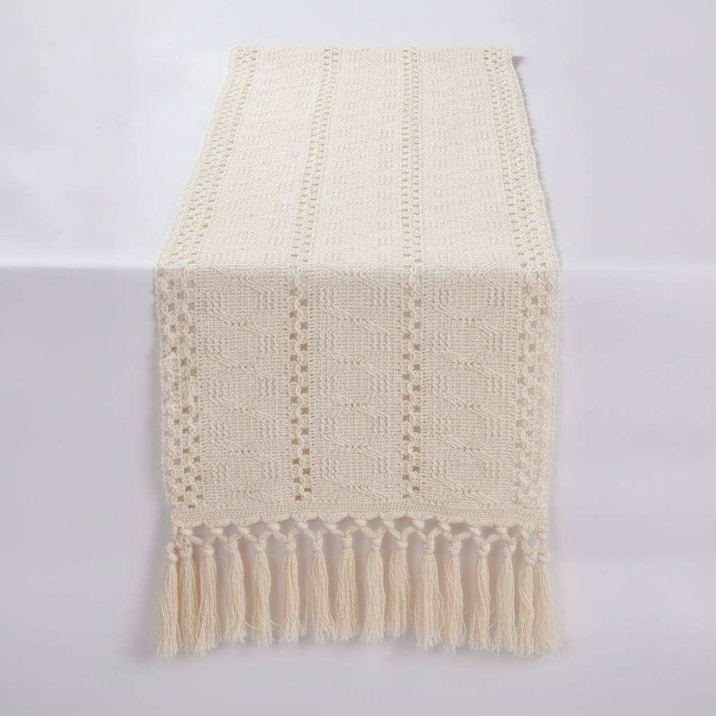 Ivory macrame cotton table runner with openwork weave and hand-knotted tassels, draped on a soft-white studio surface